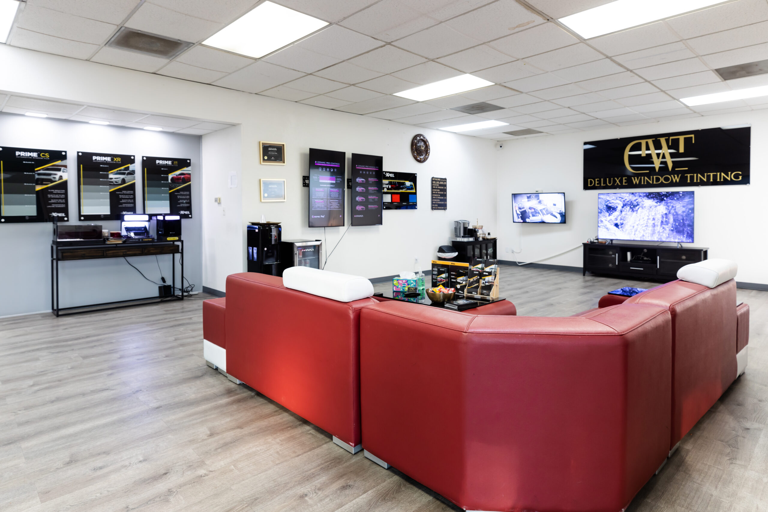 Modern customer waiting room at Deluxe Window Tinting in Gold River, CA with red leather seating and product displays.