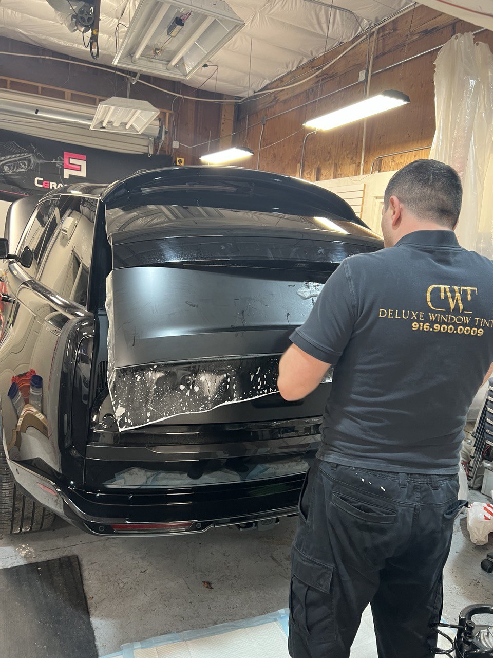 Technician applying window tint to a black SUV in Gold River, CA.