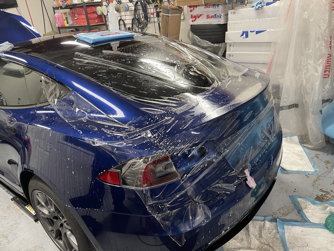 Clear paint protection film being applied to a blue Tesla at a Gold River auto detailing shop.